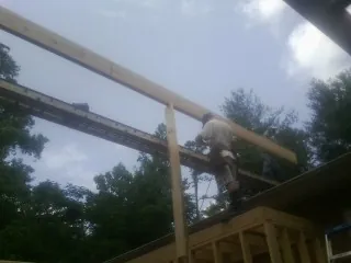 Carpenter setting a ridge beam over a new addition frame — Ice Dam Removal by Roofing Brothers in Syria