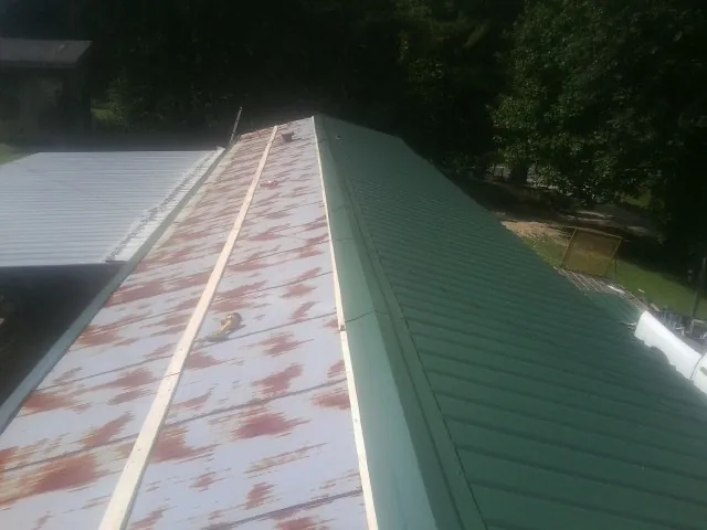 Old rusted panels beside newly installed green metal roofing — Wind Damage Roof Repair by Roofing Brothers in Syria