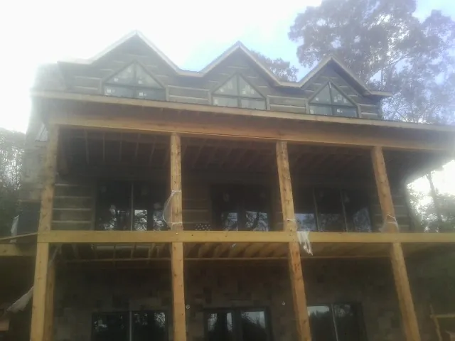 Dormers and porch framing on a large log home under construction — Roof Coating work by our crew in Syria