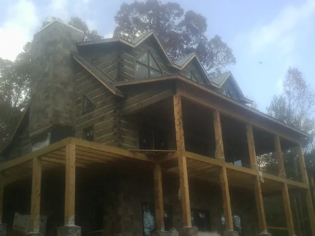 Stone chimney and dormers on a large log home with a timber porch in Syria