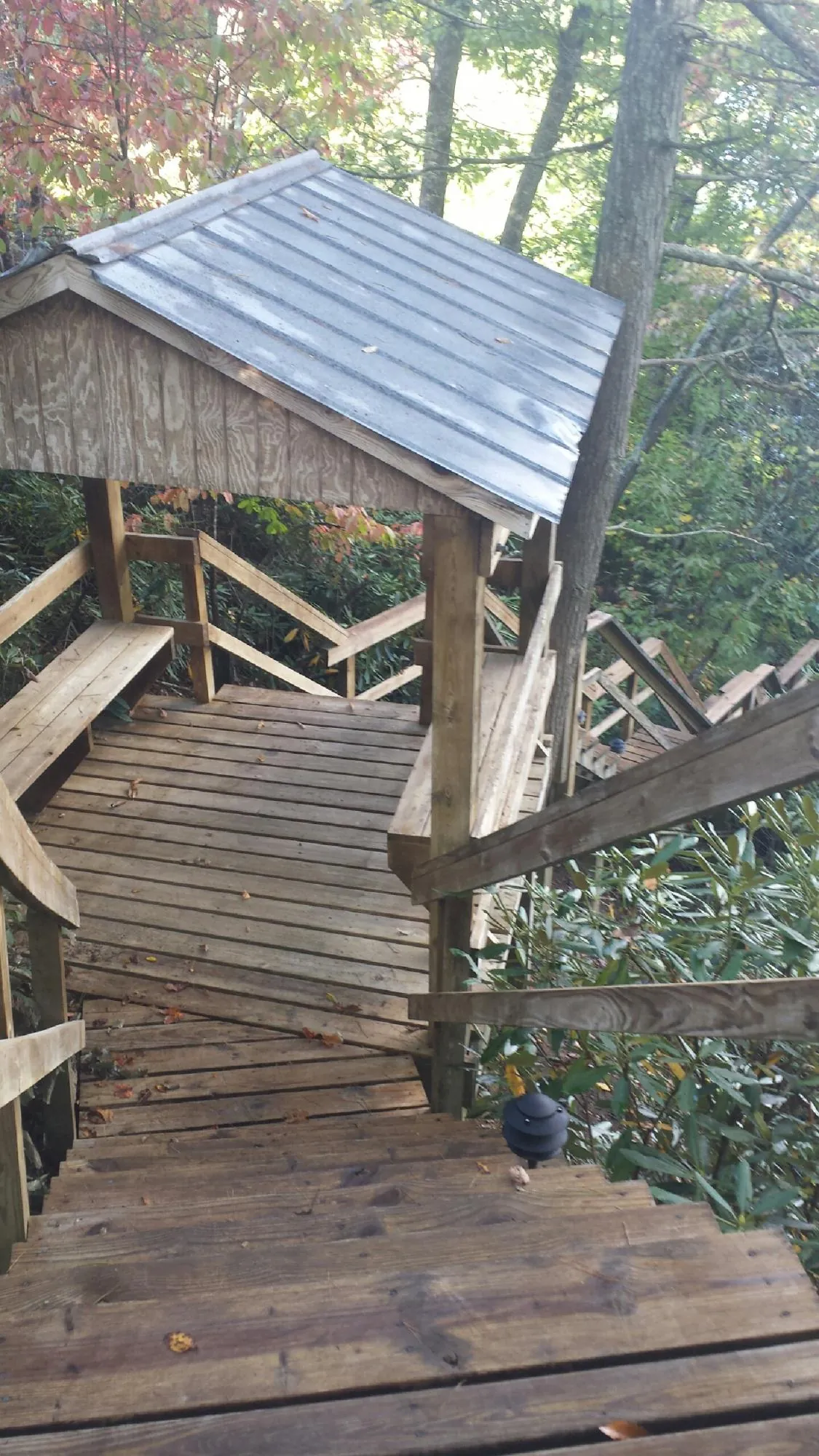 Metal roofed shelter over wooden steps on a wooded walkway — Skylight Repair & Installation work by our crew in Syria