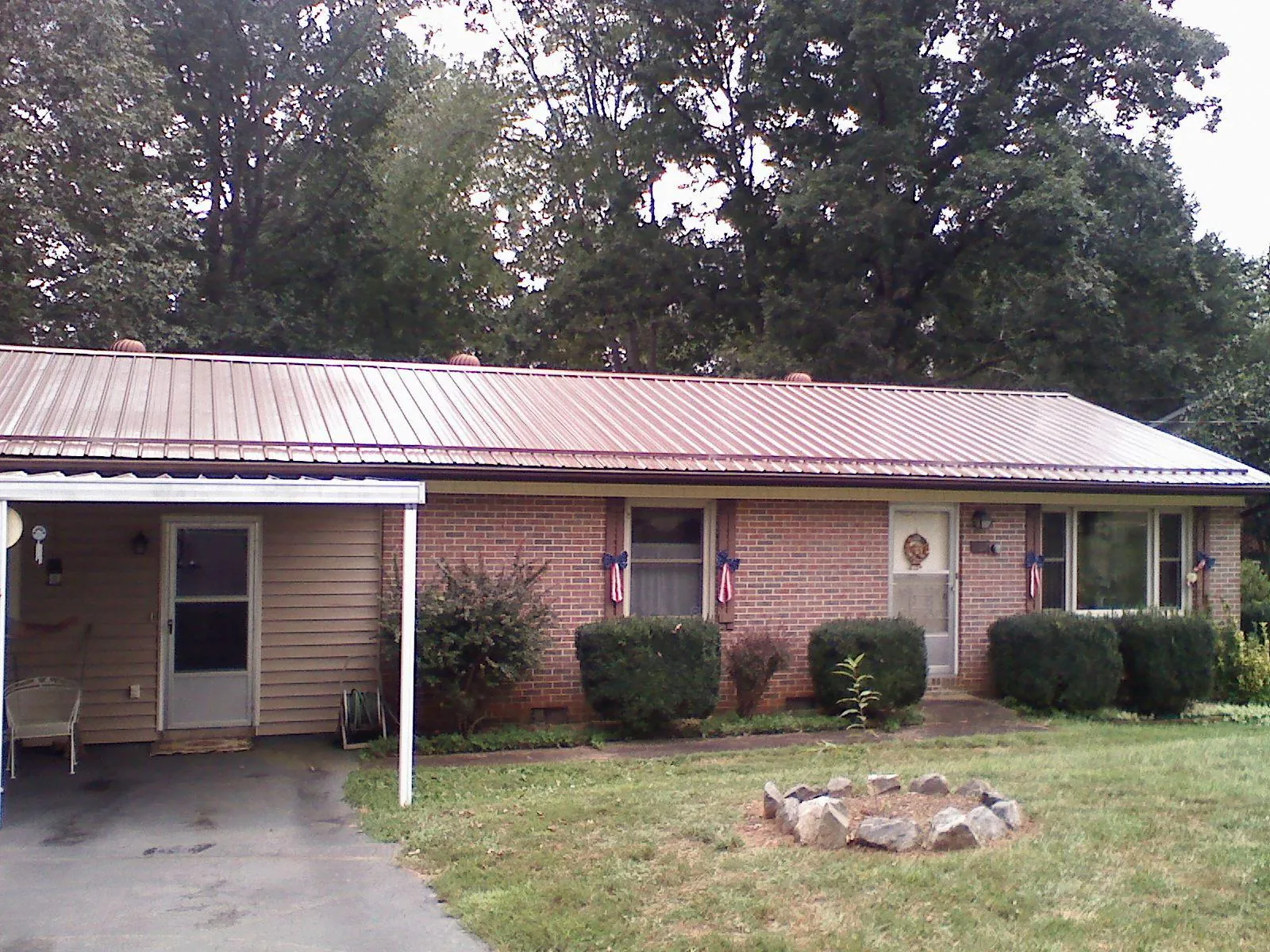 Bronze metal roof and carport on a brick ranch home — Roof Repair work by our crew in Syria