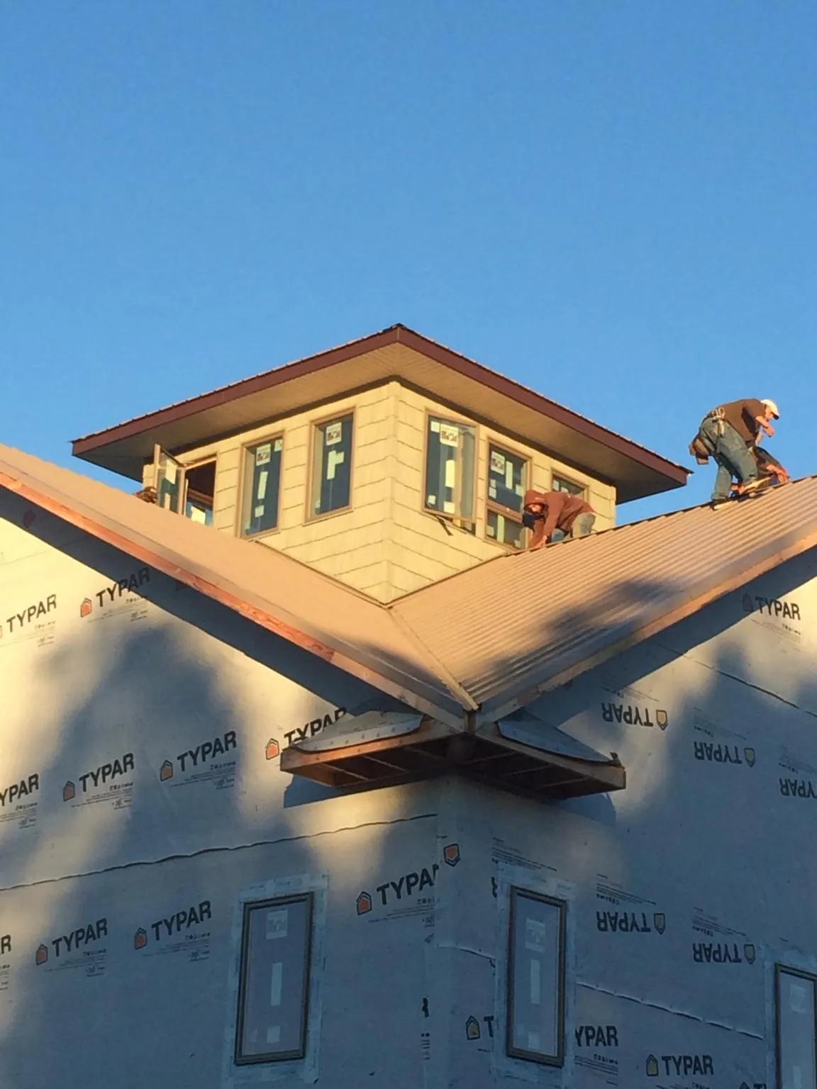Roofers working around a rooftop cupola on a new metal roof at sunset — Roof Waterproofing in Syria by Roofing Brothers